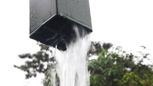 rain water coming out of rainwater pipe, droplets. rainy day