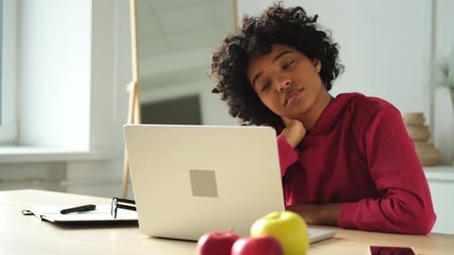 African American Woman Sitting at Table Stretching Massaging Neck Taking Break From Work on Laptop