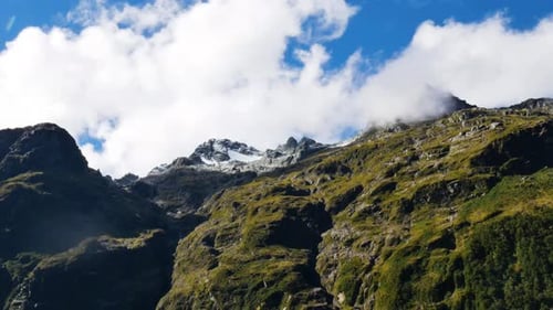 Zeitraffer von unten nach oben: spektakuläre Wolkenlandschaft, die an einem Sommertag Schneeberge und Gipfel bedeckt