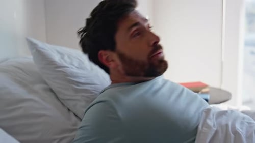 Man Wakes Up and Stretches in Bed