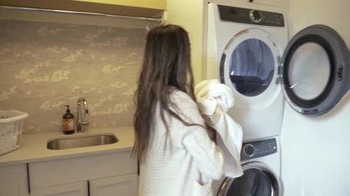 Pregnant Woman Doing Laundry In Laundry Room
