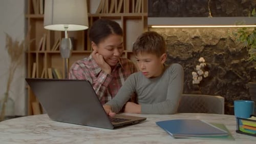 Woman and Child Use Laptop Together at Table
