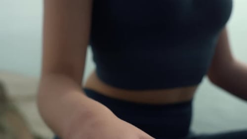 Femme détendue assise pose de lotus pratiquant le yoga sur la plage de la mer en gros plan