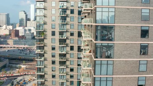 Rising aerial of large modern city urban apartment building. Daytime with glass windows and balcony