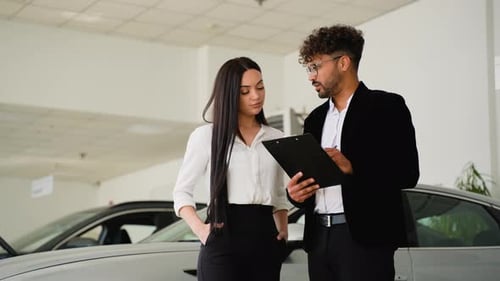 Car Salesman Showing Contract to Woman in Dealership