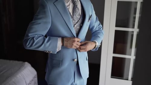 Man buttons up suit jacket in room