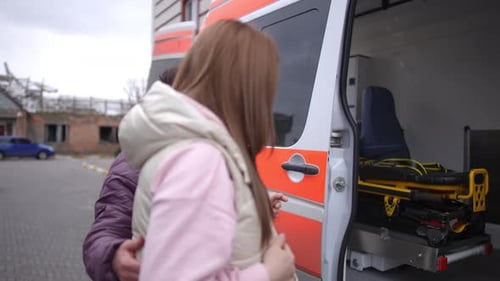 Paramédica de ambulancia que ayuda a una niña embarazada a subir a la ambulancia