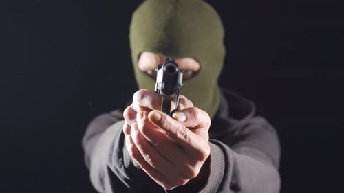 Dangerous man in mask is pointing a gun. Crime concept.