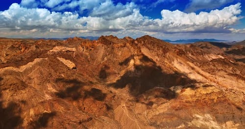 Fluffy clouds float in the sky above the rocks of Mojave desert.