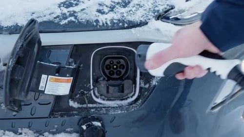 Electric Car Being Plugged In on Snowy Day