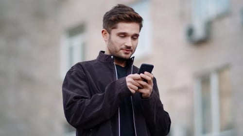 Smiling man interacting with phone in outdoor setting