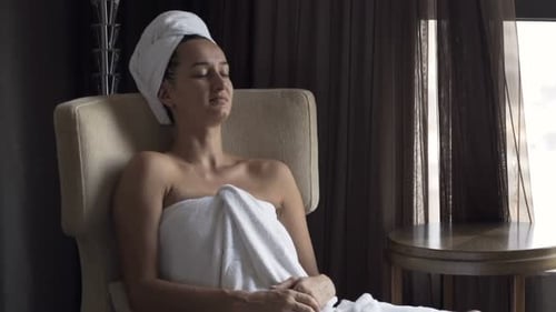 Woman Relaxing in Chair Wrapped in White Towel