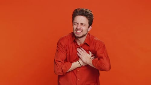Stressed Sick Young Man Suffers From Tension Holding Chest with Heart Pain Attack Risk of Stroke