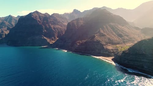 Scenic drone view of virgin beach with torquoise water seascape surrounded by mountain at sunrise
