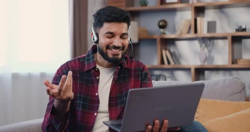 Young Adult Using Laptop Computer With Headset