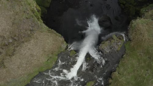 Above powerful Kvernufoss waterfall, water falling over edge of cliff, aerial