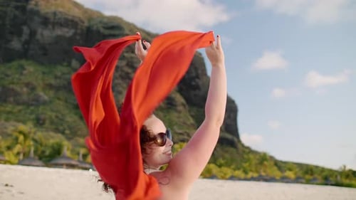 Joyful Moment: Woman with Red Scarf on a Sunny Beach Day