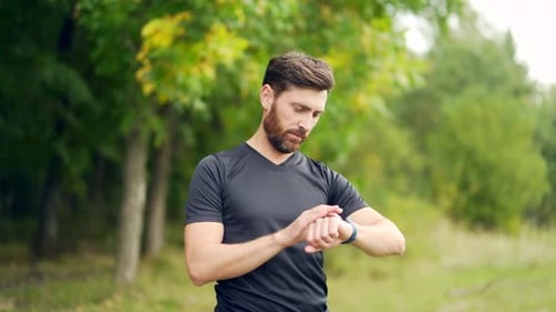 Man Checks Smartwatch During Outdoor Exercise