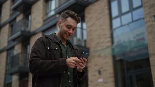 Smiling Man Using Smartphone Outside Building