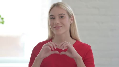 Young Woman Makes Heart Shape with Hands