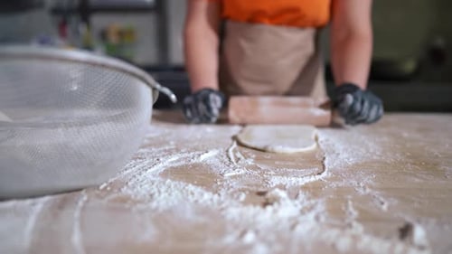 Baker Rolling Dough with Rolling Pin in Kitchen