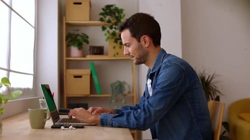 Young Adult Man Working on Laptop Computer at Home Studio