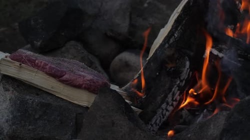 Filete cocinado en un trozo de leña junto a una fogata