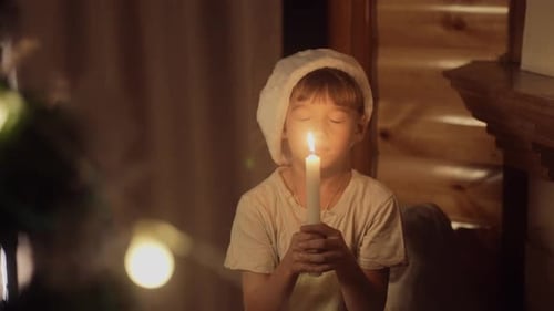 Young Boy Wearing a Santa Hat Blowing Out a Candle on Christmas and Make a Wish