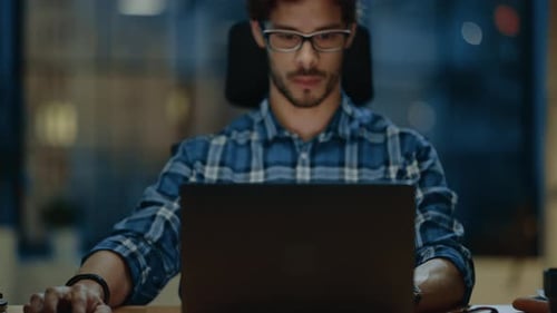 Man Working on Laptop at Desk Late at Night