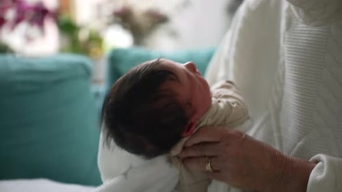Grandmother Burping Newborn Baby Wrapped in Soft Blanket