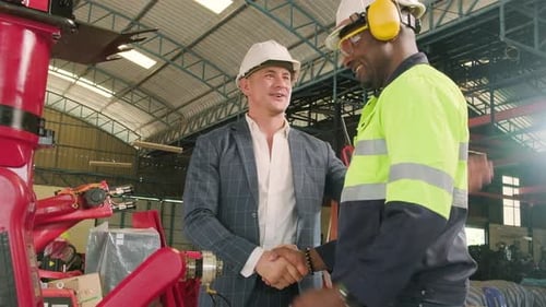 Black engineer handshakes with customer with robotic arm in a smart factory.
