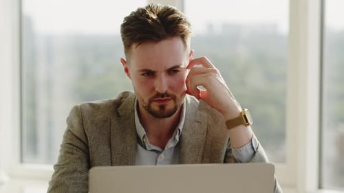 Handsome Businessman Working in an Office Space Focused Young Man Sitting with Laptop and Thinking