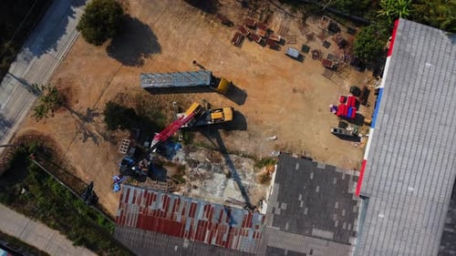 Mobile crane stands waiting to lift steel at a warehouse. Crane operators and mobile cranes