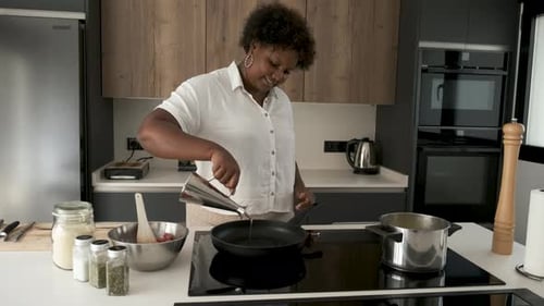 Woman Cooking Meat in a Modern Kitchen