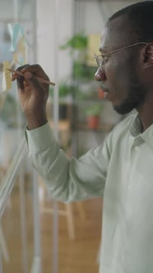 Man Writing on Glass in Office Space