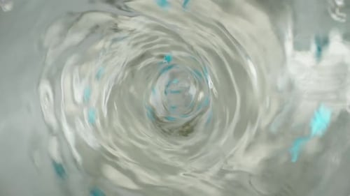 Whirlpool or funnel in water. Macro shooting. I throw blue stars into the water, slow motion.