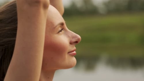 Closeup Young Woman Stretches Her Arms Up Doing Yoga Against the Background of a Pond