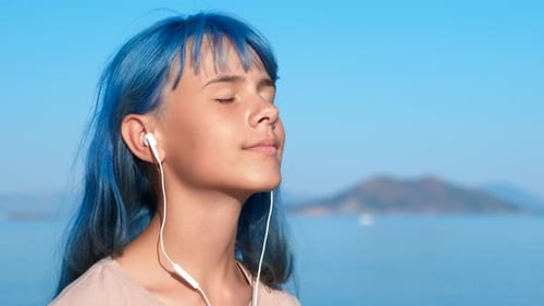 Adolescente azul con música cerca del agua