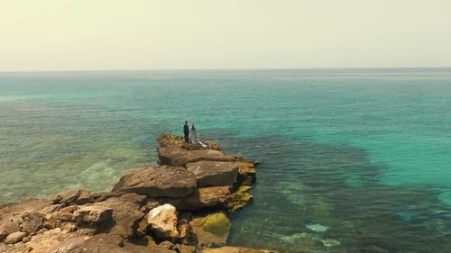 Serene Coastal Scene with a Couple Standing on a Cliff Above the Sea