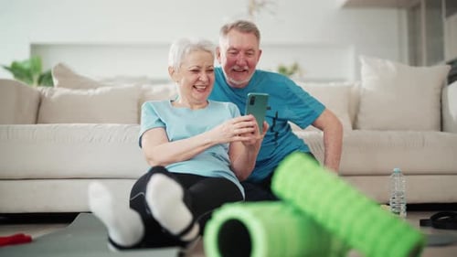 Senior Couple Smiles at Phone After Home Workout