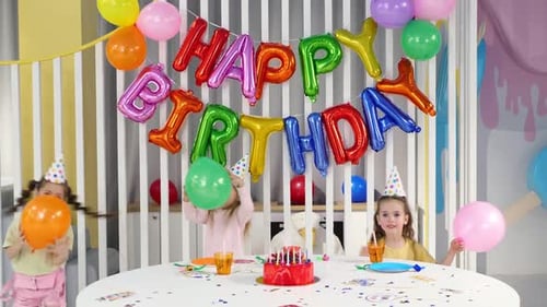 Girls Celebrate Birthday Party with Cake and Balloons