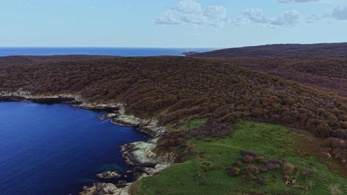 Scenic aerial view of a coastal landscape with hills and clear sea