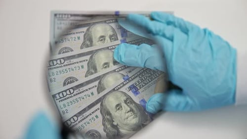 Magnifying Glass Inspecting One Hundred Dollar Bills