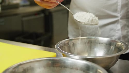 Cook adding flour to bowl with spoon