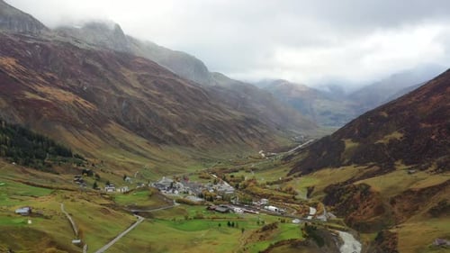 rainy Aerial View on Grimselpass high mountian alpine road, river, houses and Swiss Alps in backgrou