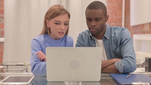 Young Adults Collaborating on Laptop in Modern Office