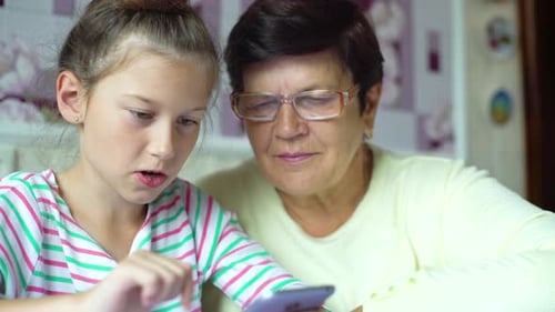 Child and Adult Looking at Tablet Together Indoors