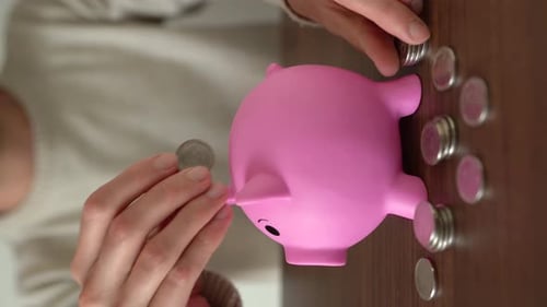 Vertical shot of a person keeping money in his piggy bank. Side view.