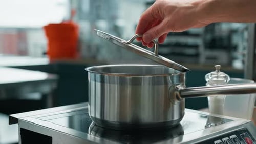 professional kitchen chef checks the readiness of the dish by lifting the lid of the pot food