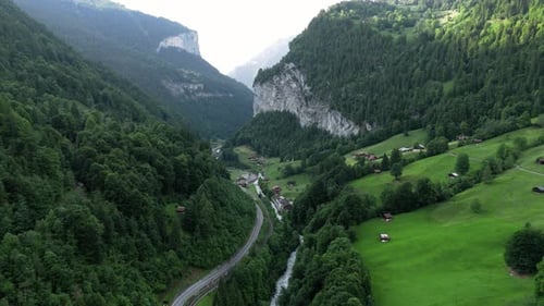 Flyinge over the forresty and mountainous alp valley of grindelwald Switzerland Lauternbrunnen creek